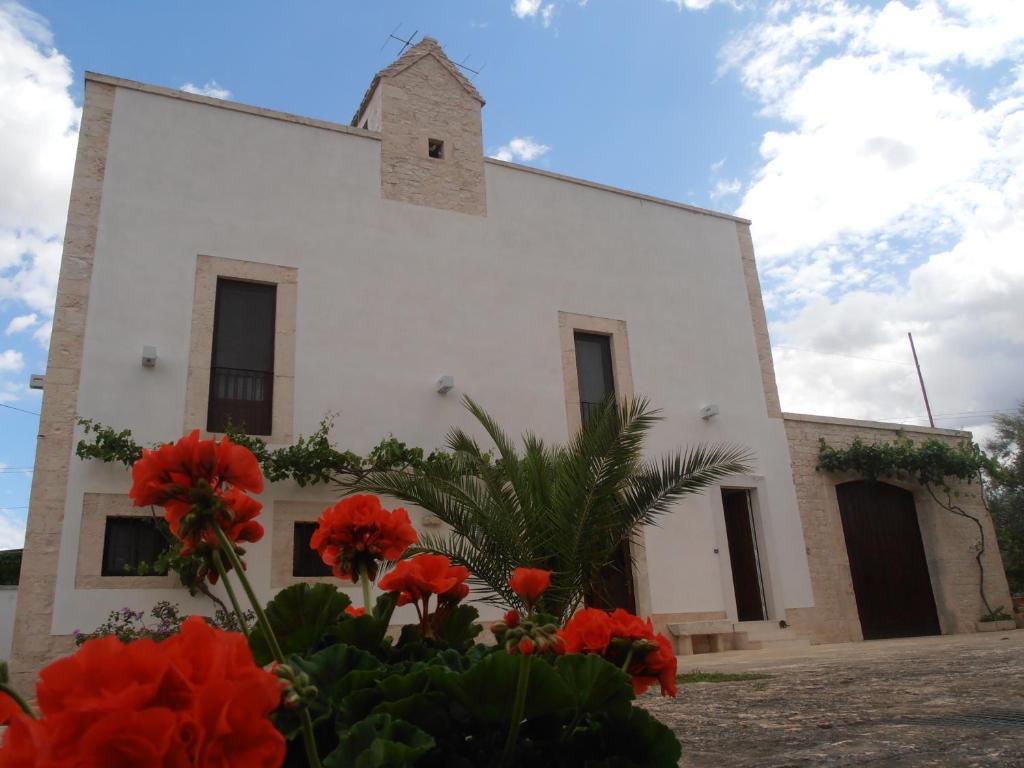 una iglesia con flores rojas delante de ella en Masseria Nonna Angela, en Putignano
