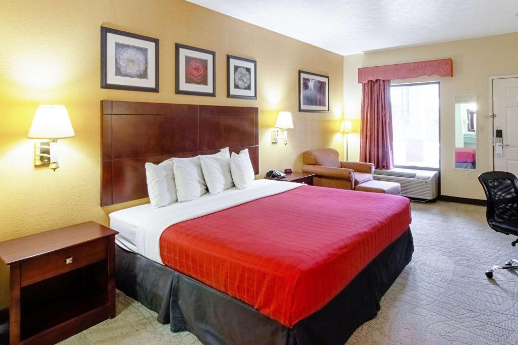 a hotel room with a large bed with a red blanket at Quality Inn & Suites in Dickson