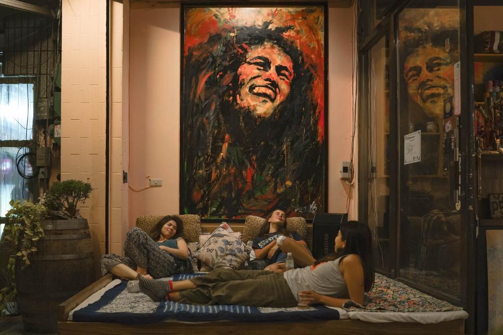 un grupo de mujeres tumbadas en una cama frente a una pintura en Dulan The Travel Bug Bistro Inn en Donghe