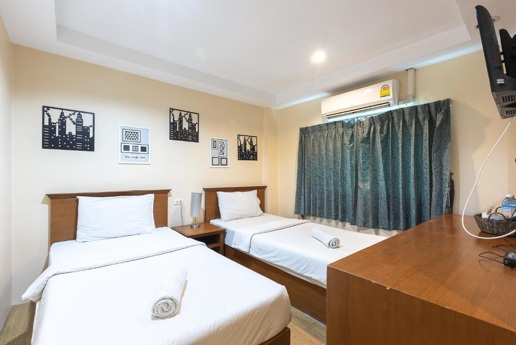 a room with two beds and a desk and a window at Sleep at Phuket SHA Plus in Phuket Town