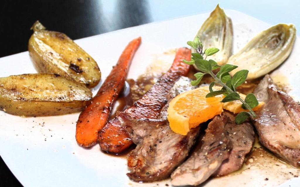 a plate of food with meat and carrots and potatoes at Hotel La Peyrade in Cajarc