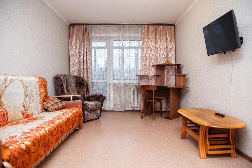 a living room with a couch and a table and a television at Apartments at Michurina 15 in Kemerovo