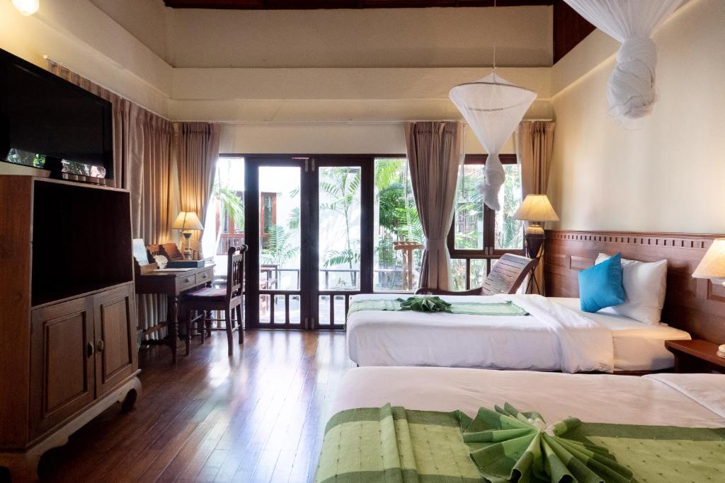 a bedroom with two beds and a desk and a television at Royal Lanta Resort & Spa in Ko Lanta