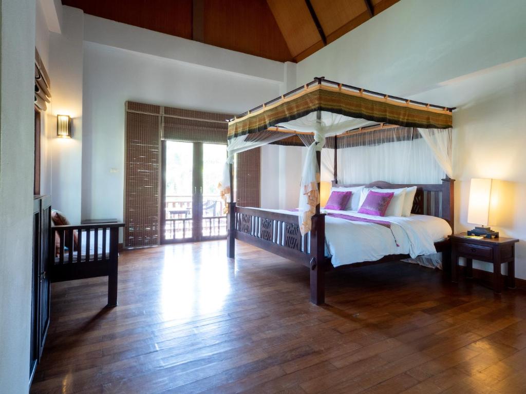 a bedroom with a canopy bed and a wooden floor at Royal Lanta Resort & Spa in Ko Lanta