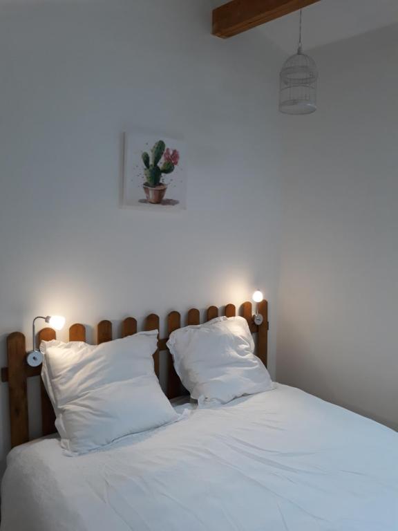 1 cama con sábanas y almohadas blancas y una planta en la pared en Pigeonnier Brens, en Brens