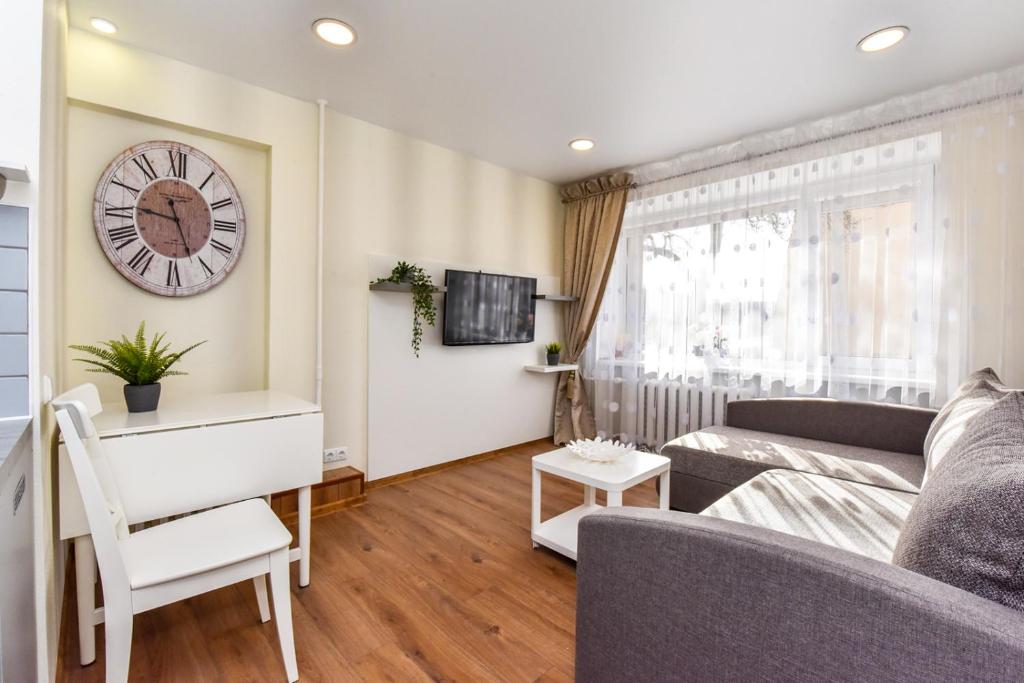 a living room with a couch and a clock on the wall at Baltieji Senamiesčio Apartamentai prie Aqua Parko in Druskininkai