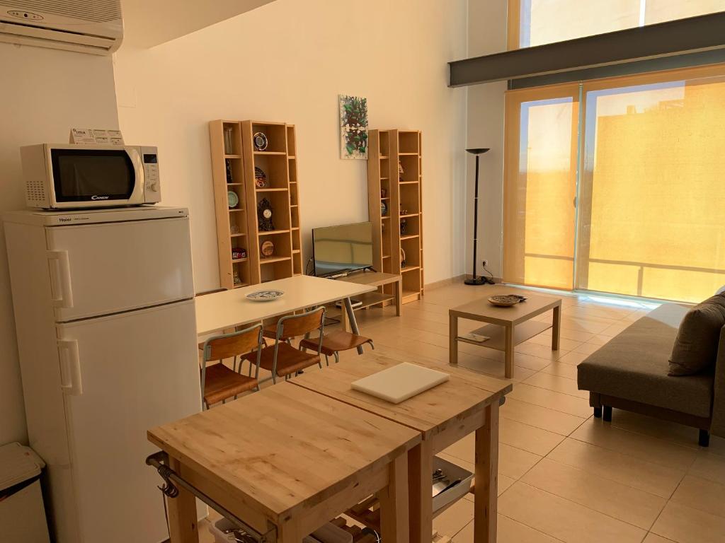 uma cozinha e sala de estar com um frigorífico e uma mesa em Apartamento de 1 dormitorio, Ático 4PAX em Alcorcón