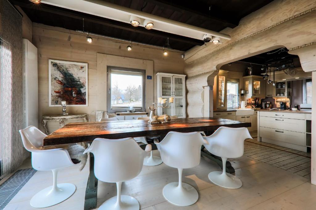 une cuisine avec une grande table en bois et des chaises blanches dans l'établissement Kwiat Śniegu DeLuxe Koło Gubałówki, à Nowe Bystre