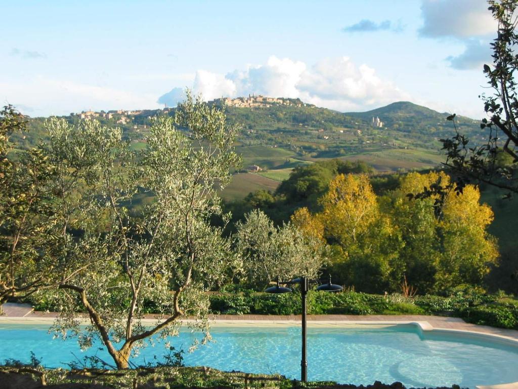 una piscina con árboles y montañas en el fondo en Agriturismo Colle di Mezzo, en Montefollonico