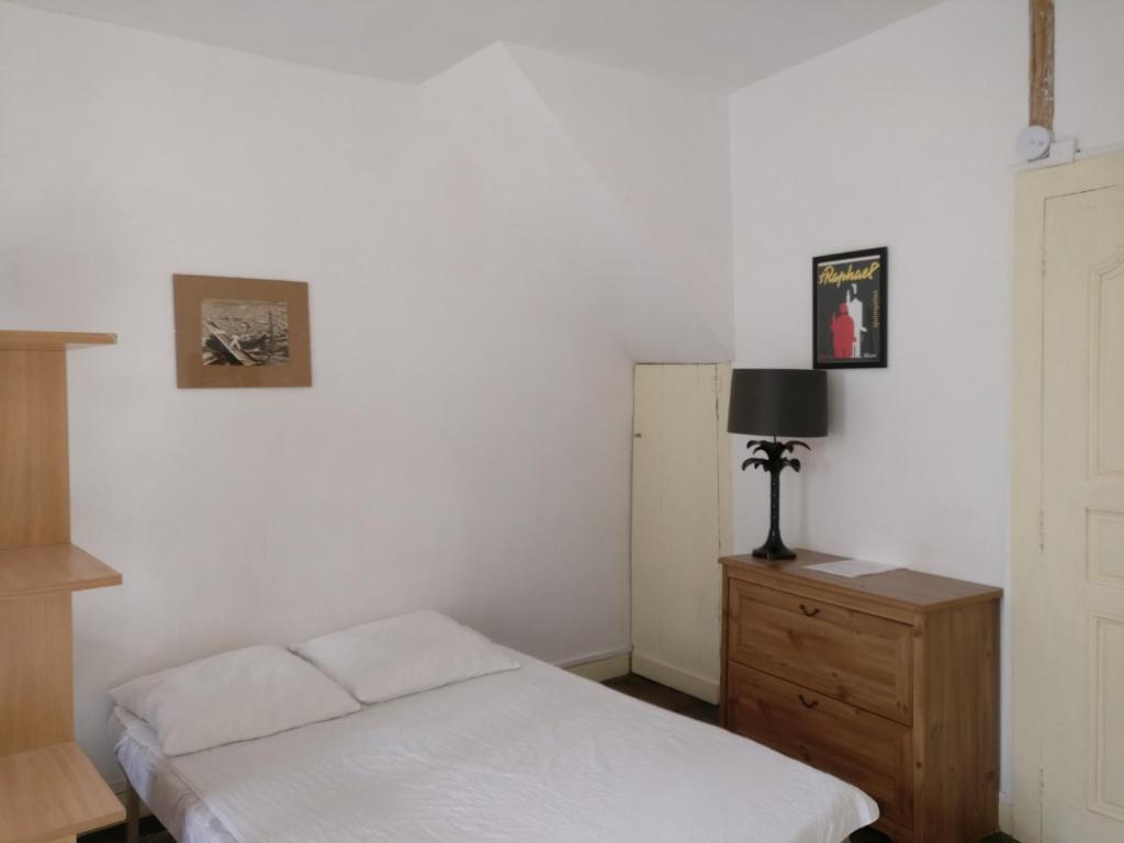 um quarto com uma cama branca e uma cómoda em madeira em Studio Les Armuriers em Condom