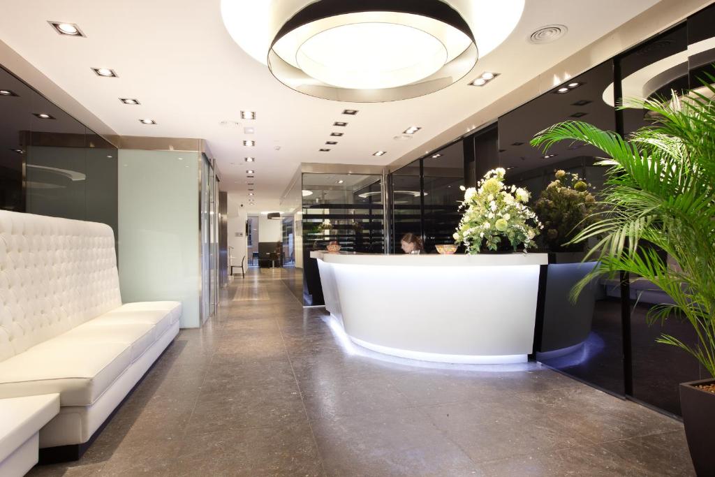 a lobby with a white counter and plants at Dalia Ramblas in Barcelona