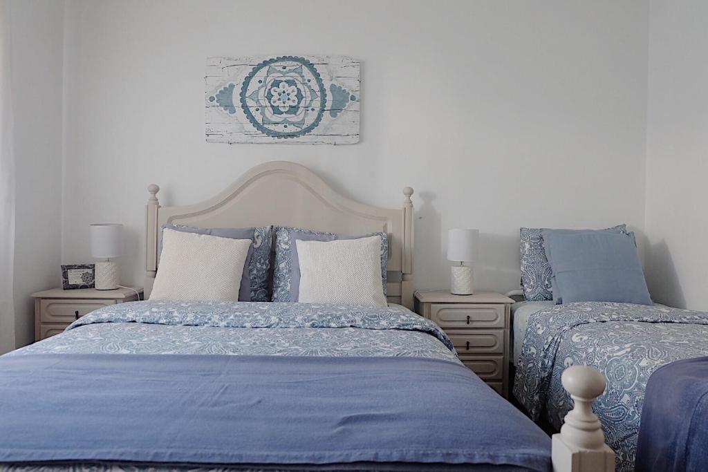 two beds in a bedroom with blue and white at Refúgio do Almograve in Almograve