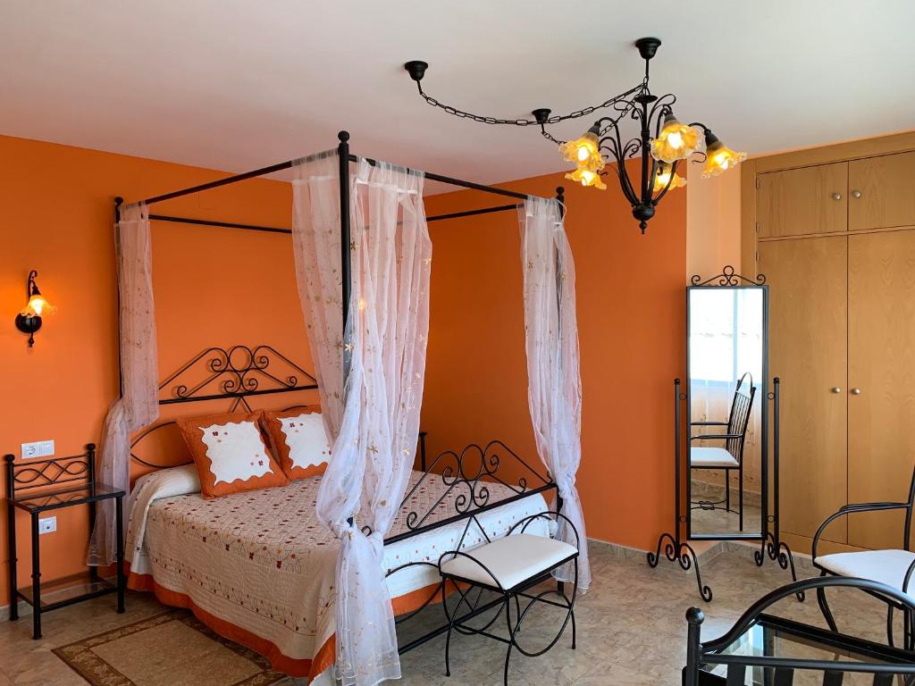 a bedroom with a canopy bed with orange walls at Alacena Alfarera in Pereruela