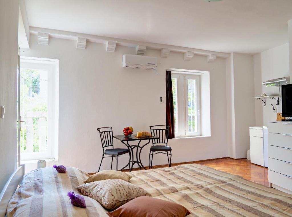 1 dormitorio con 1 cama y 1 mesa con sillas en White House Apartments, en Korčula