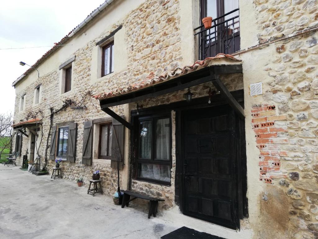 un edificio in mattoni con una porta e una panca all'esterno di Algarabiastaying 3 granja San Julián a Medina de Pomar