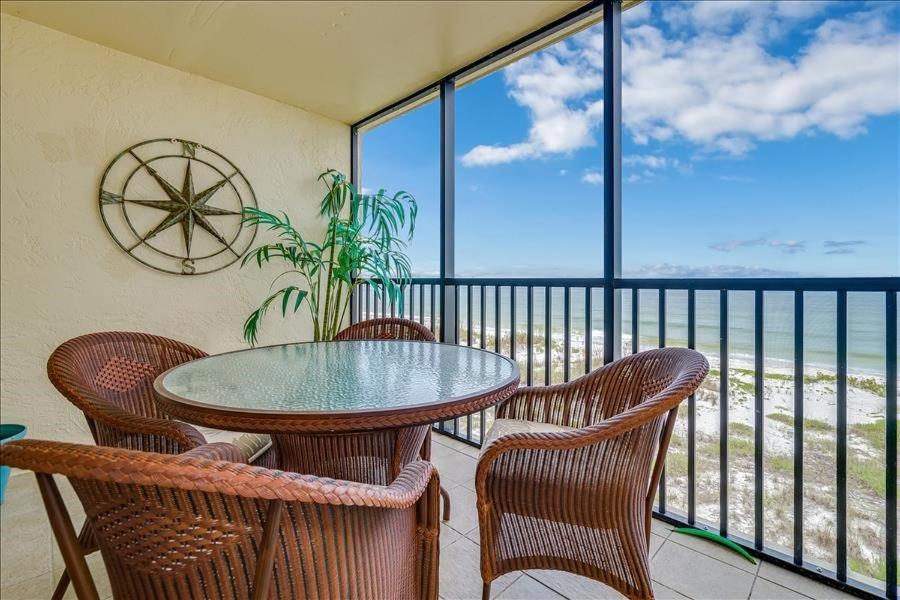 a table and chairs on a balcony with a view of the ocean at Sea Oats 217 Condominium Condo in Boca Grande