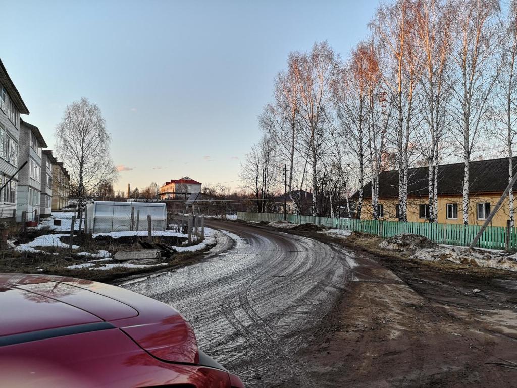 ジヴェエヴォにあるDiveevskoe podvorieの木々や家々が立ち並ぶ未舗装道路を走る車