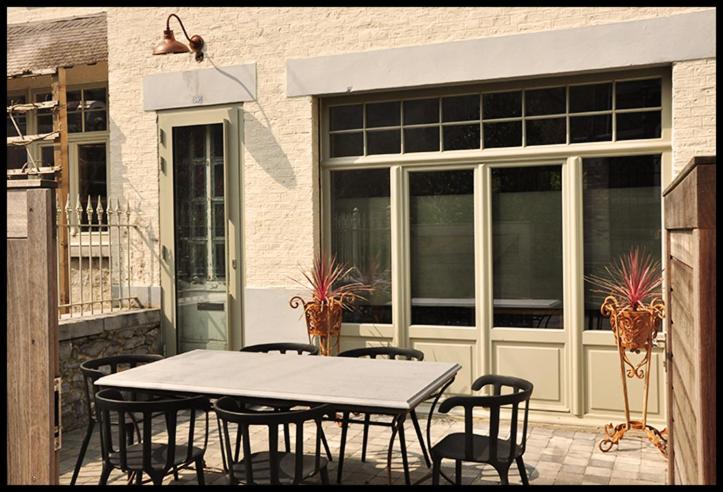 un patio con mesa y sillas y un edificio en Een thuis in de Condroz, en Waulsort