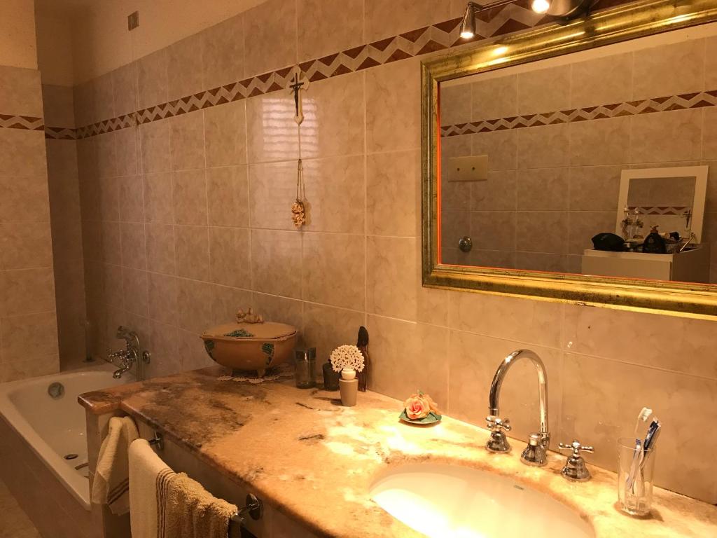 e bagno con lavandino, specchio e vasca. di Bristol apartment a Capo dʼOrlando