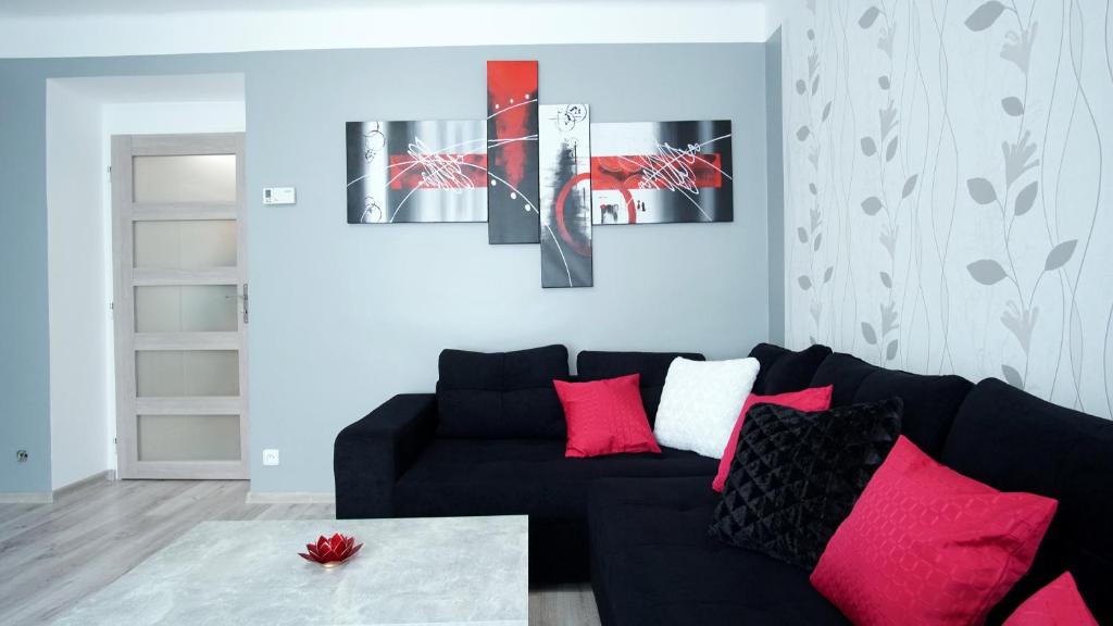 a living room with a black couch and red pillows at Apartmány Monty in Karlovy Vary