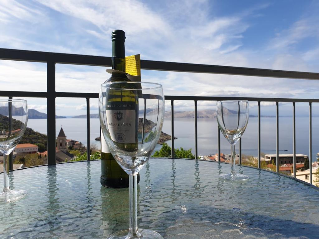 a bottle of wine sitting on a table with two wine glasses at Slavica apartments 3 in Sveti Juraj