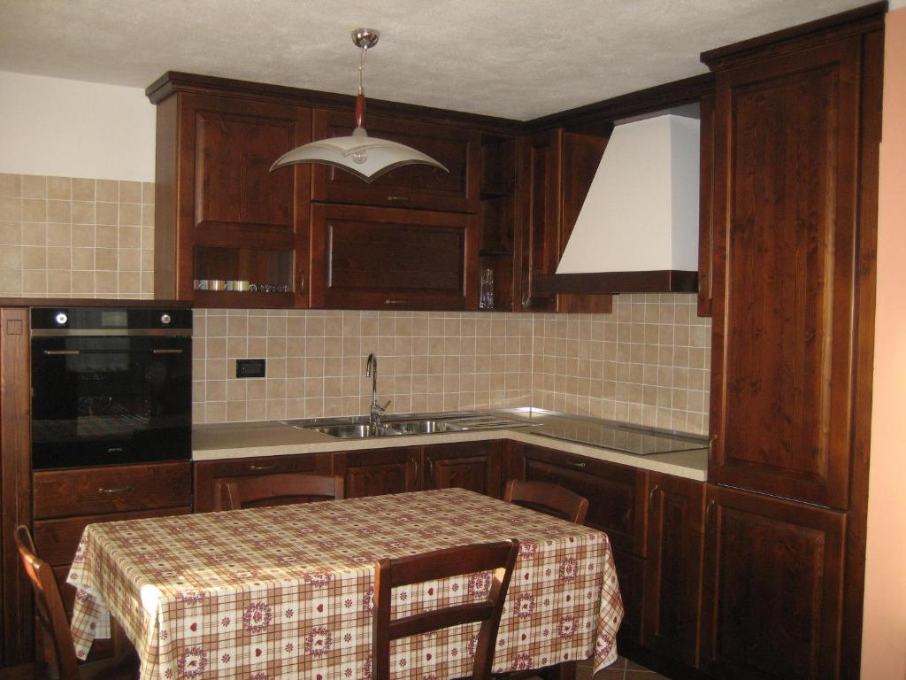 una cocina con armarios de madera, mesa y fregadero en Deliziosa casetta, en Valpelline