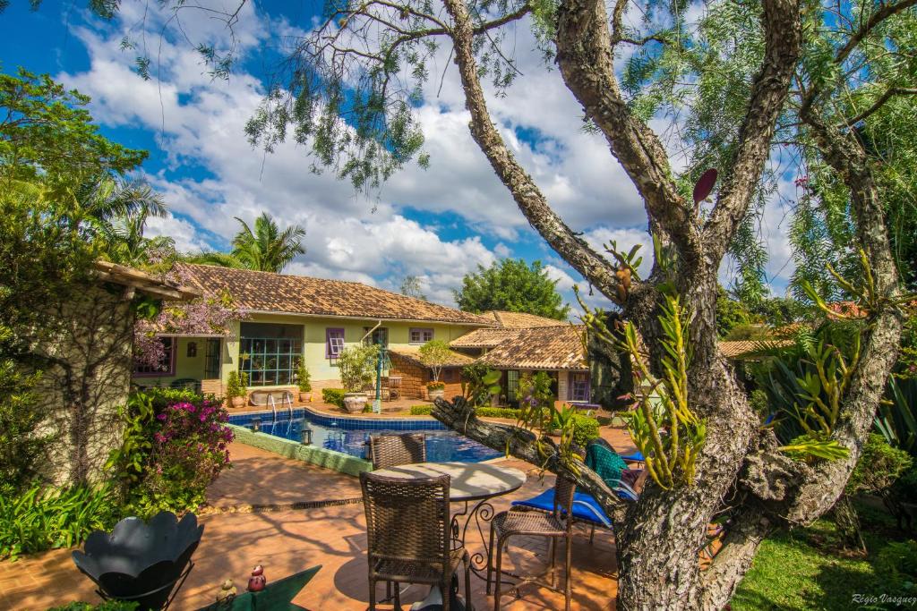 a house with a swimming pool and a tree at Pousada Villa Allegra in Tiradentes