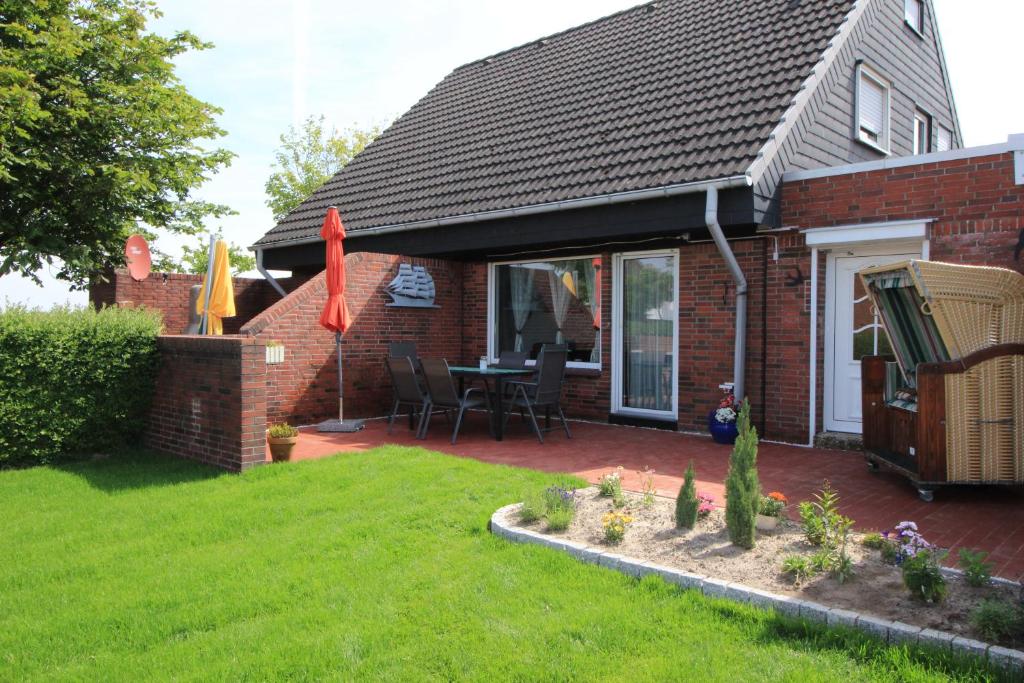 a house with a patio with a table and chairs at Ferienhaus**** Wind und Wolke in Friedrichskoog-Spitze