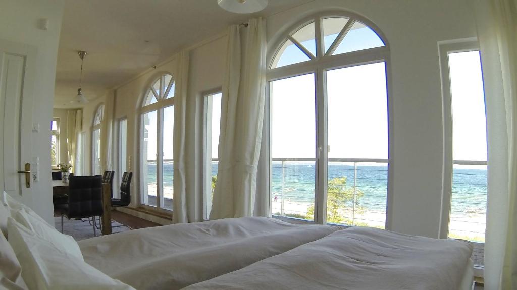 een slaapkamer met een bed en uitzicht op de oceaan bij Strandhuus - Urlaub aan de Ostsee in Timmendorfer Strand