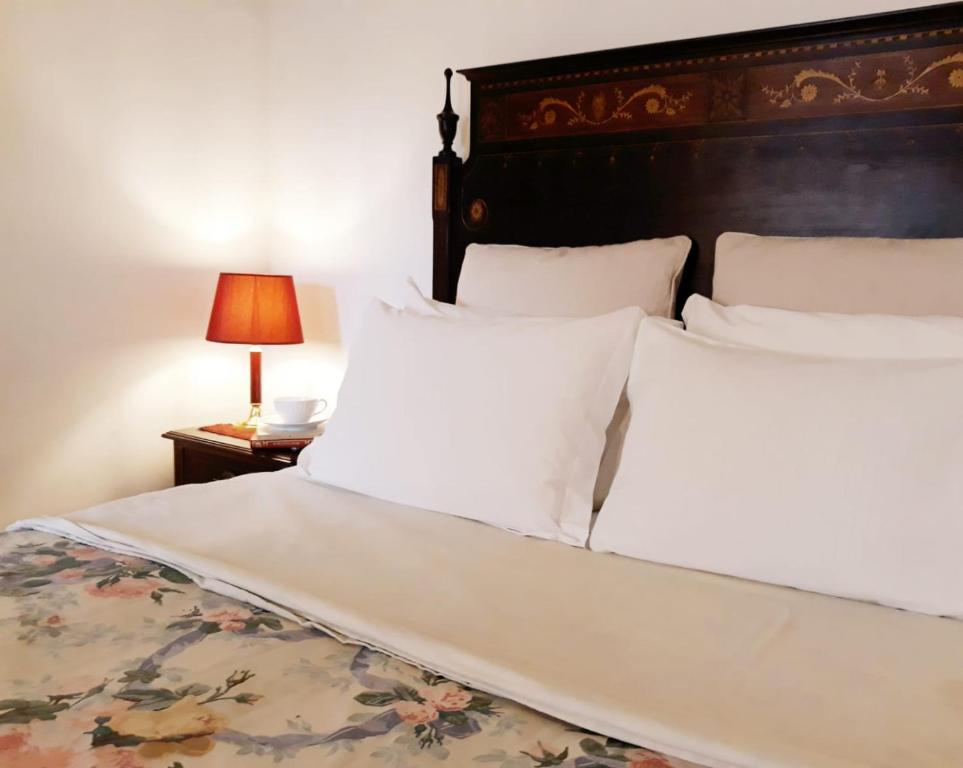 ein großes Bett mit weißen Kissen und einem Tisch mit einer Lampe in der Unterkunft Casa Das Obras in Manteigas