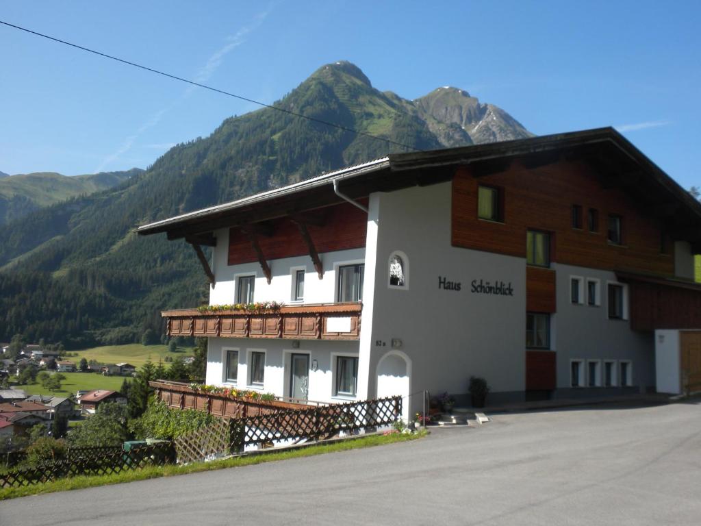 a large white and brown building with mountains in the background at Haus Schönblick in Bach