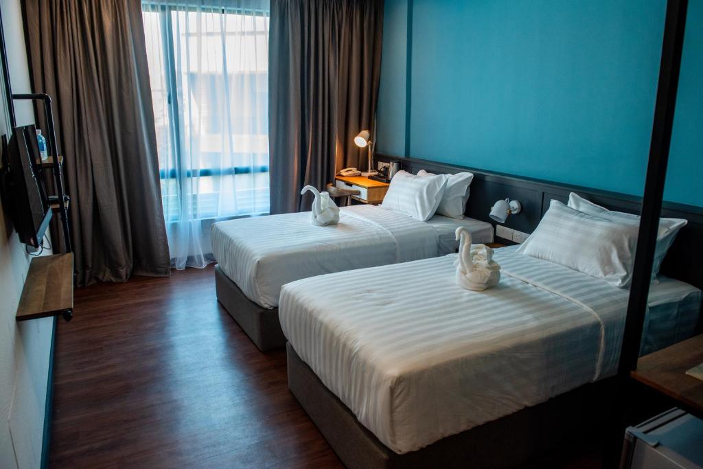 two beds in a hotel room with blue walls at O&G Hotel Parit Buntar in Parit Buntar