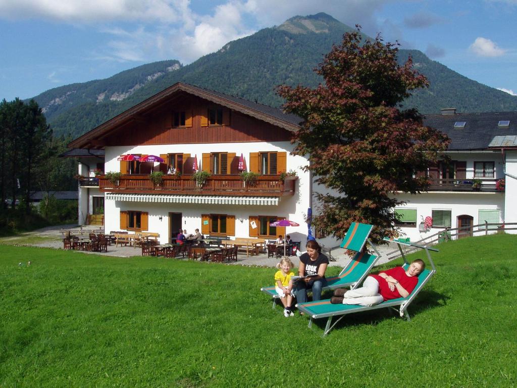 un grupo de personas sentadas en sillas de jardín frente a una casa en Hotel Garni Pension zur Wacht, en Strobl