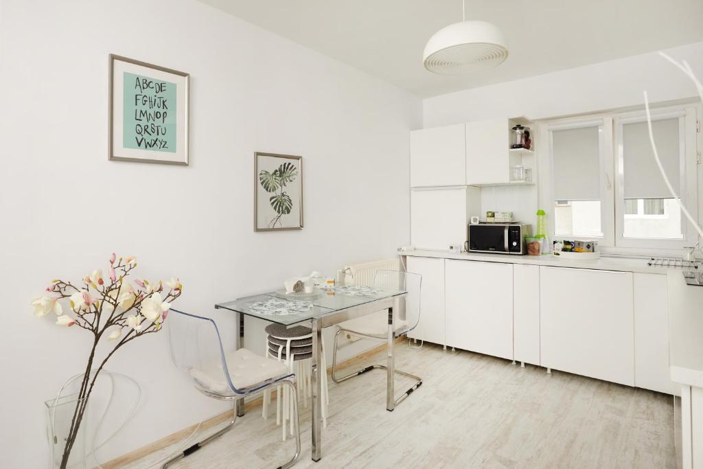 a kitchen with white cabinets and a table and chairs at Vama Apartment in Sinaia