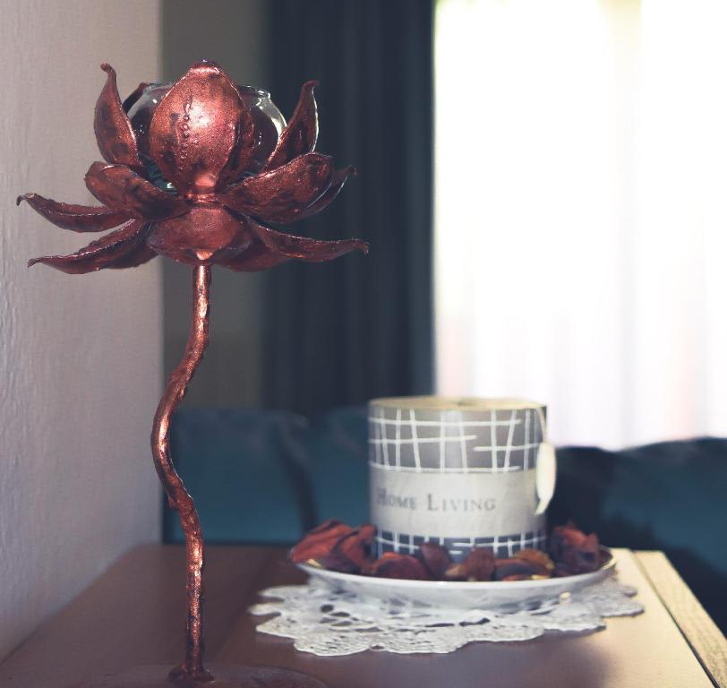 un fiore rosso su un tavolo accanto a una tazza di La casa del viaggiatore a Codrongianos