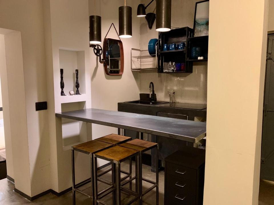 uma cozinha com um balcão, um lavatório e bancos em Fra Storia e Modernità em Milão