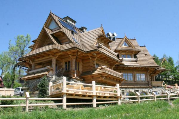 uma grande casa de madeira com uma cerca de madeira em frente em Villa Miodula em Kościelisko