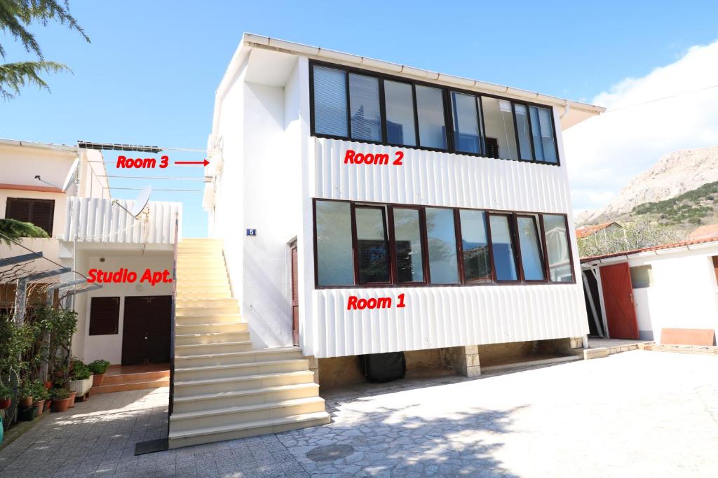 a house with names on the side of it at Rooms & Studio Apartment Mira in Baška