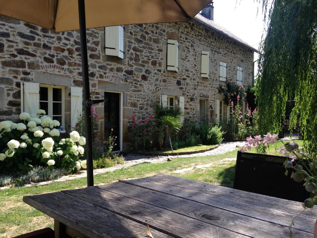 une table en bois avec un parasol devant un bâtiment dans l'établissement B&B Maison Coralie, à Sainte-Christine