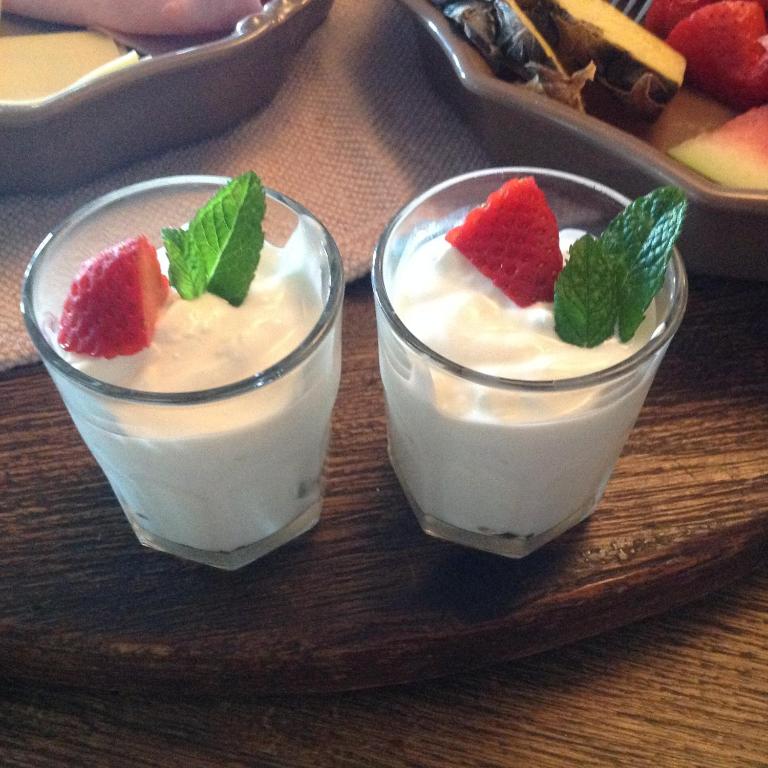 two glasses of yogurt with strawberries and mint on a tray at villaquinta in La Herradura
