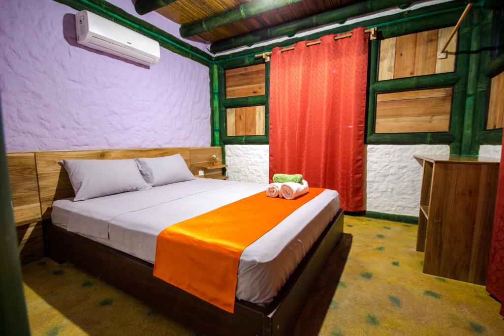 a bedroom with a bed with an orange blanket at Aparthotel Oleaje in Mompiche