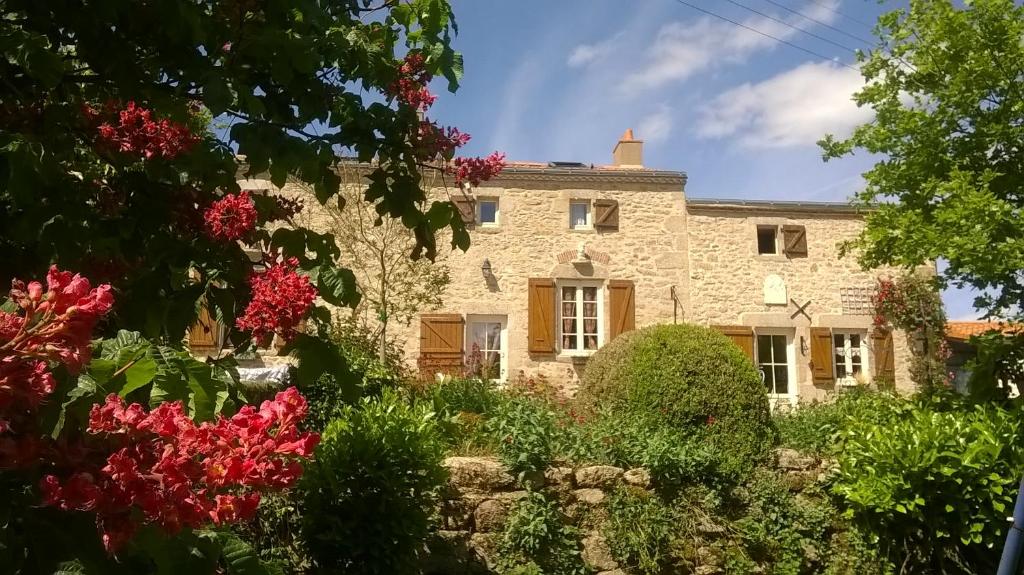 une maison en pierre avec des fleurs devant dans l'établissement Au Coeur de la Nature, à Saint-Malo-du-Bois