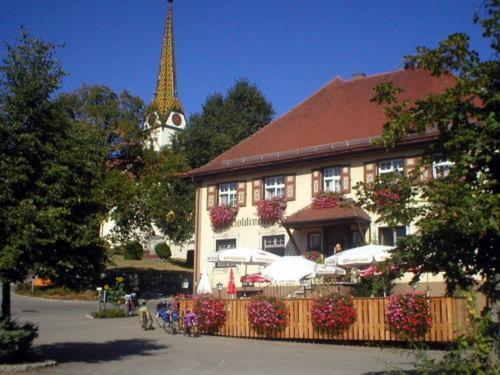 a building with a restaurant with a tower in the background at Gasthof zum Goldenen Kreuz in Wilhelmsdorf