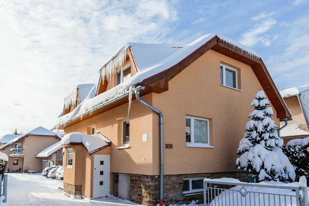 una casa con nieve en el techo en Apartmány Hrady, en Zuberec
