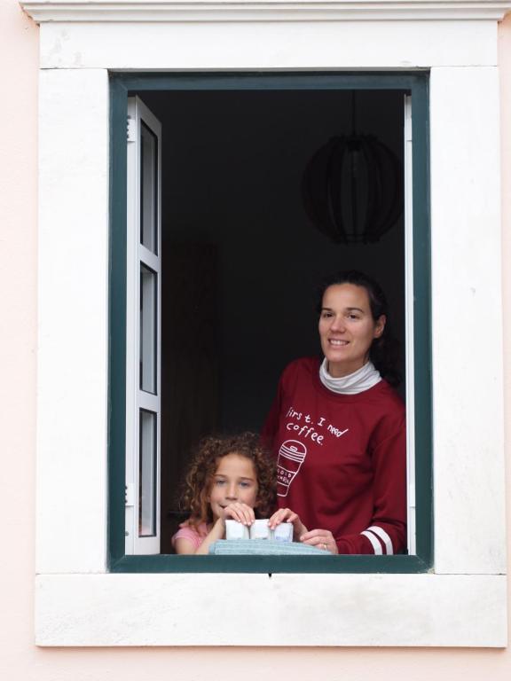 two children are looking out of a window at Casa da Tia Dulce in Pataias