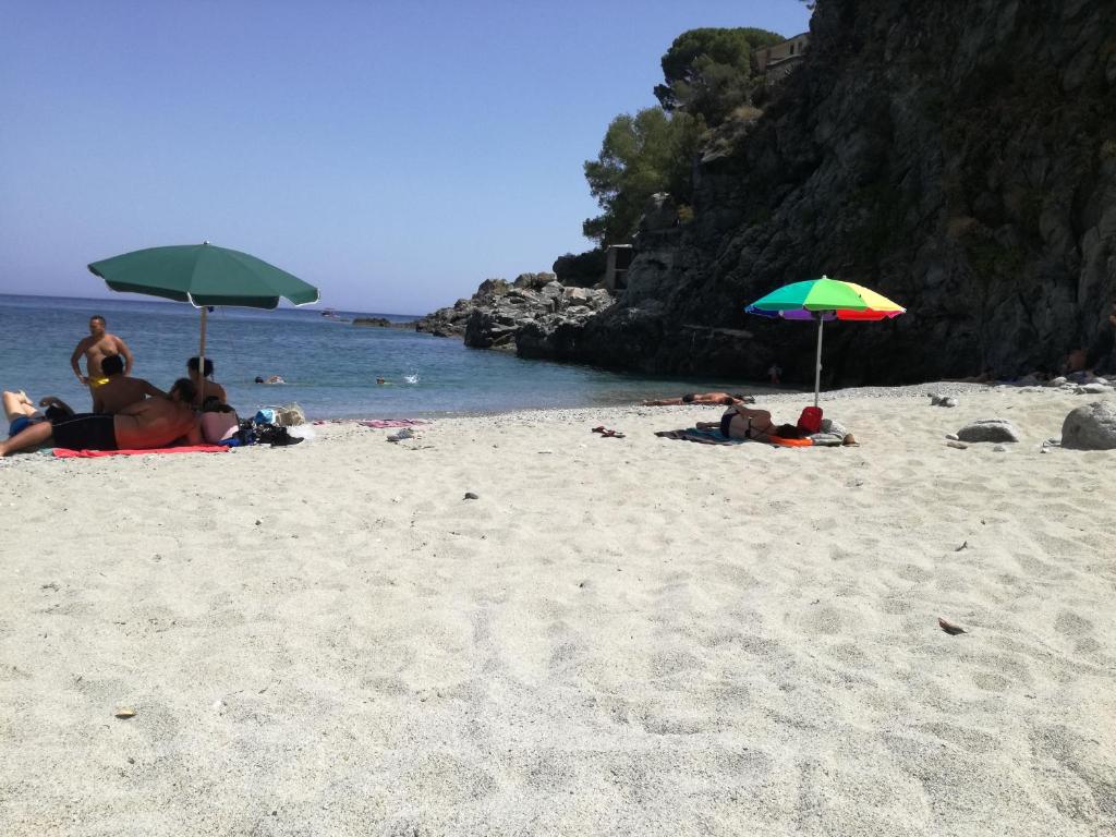 eine Gruppe von Menschen, die am Strand mit Sonnenschirmen liegen in der Unterkunft Villetta Medusa in Copanello