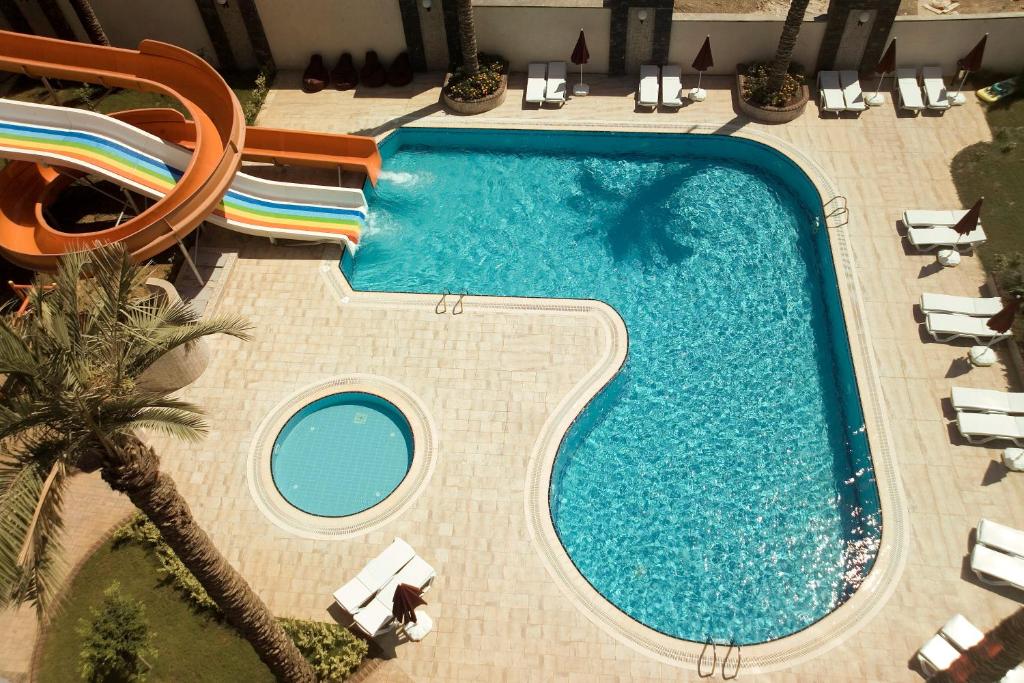 una vista aérea de una piscina con sillas y una palmera en Xperia Alanya Park Residence with large balcony and seaview & free airport shuttle service, en Alanya