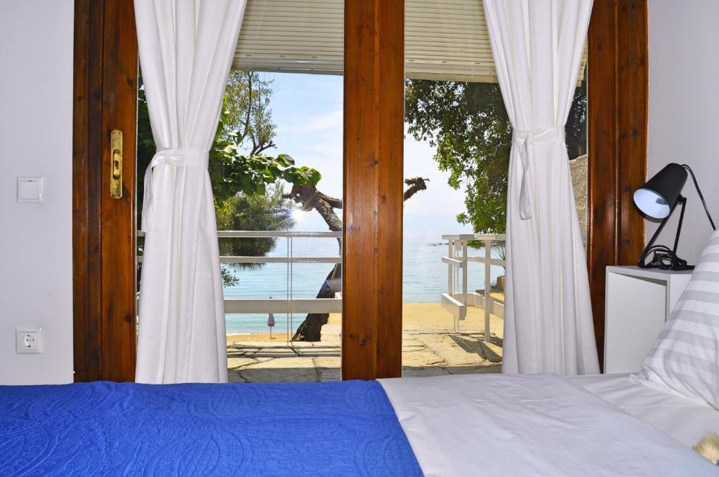 1 dormitorio con cama y vistas a la playa en Secret Bay, en Palaión Tsiflíkion