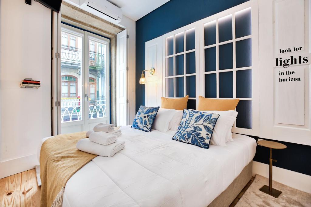 um quarto com uma cama grande com paredes azuis e uma janela em Janelas de São Bento by Porto City Hosts no Porto