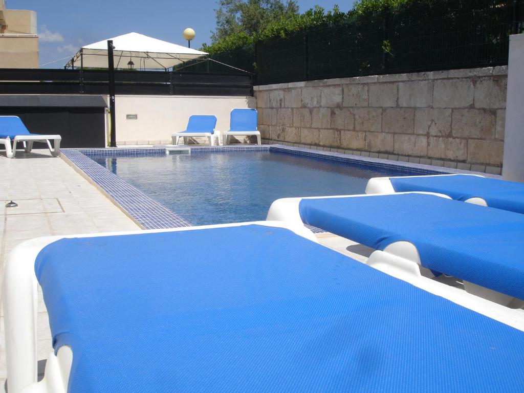 a swimming pool with blue and white chairs next to it at PICAFORT2 in Can Picafort